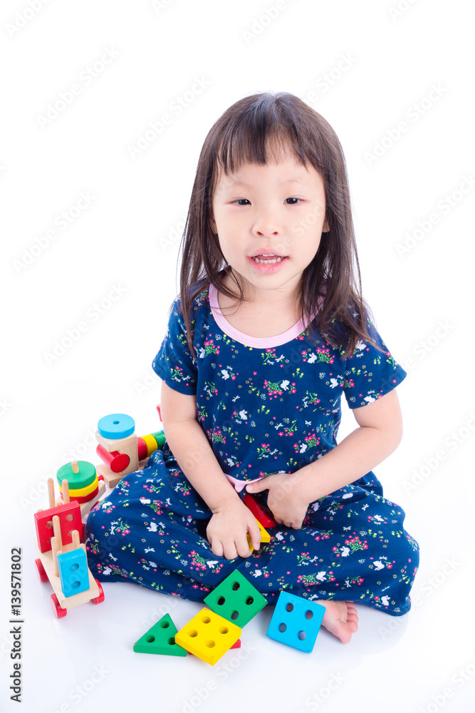 Little asian girl playing with wooden train toy over white Little asian girl playing with wooden train toy over white