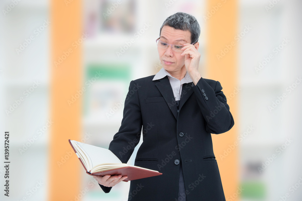 Fototapeta premium Old asian woman reading book having problem with her eyes