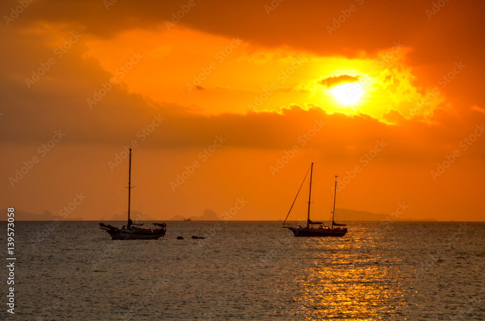 sunset over ocean with small boat silhouette