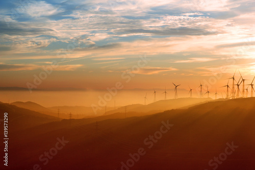 Wind turbines during sunset with Andalusian hills, Atlantic ocean and mountain of Africa on background.