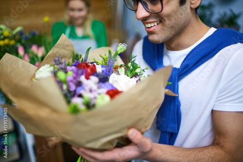 Guy smelling bouquet of flowers in florist store photo