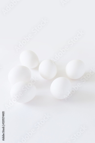 Easter decoration minimalistic white chicken eggs lying on a white background, daylight, vertical image