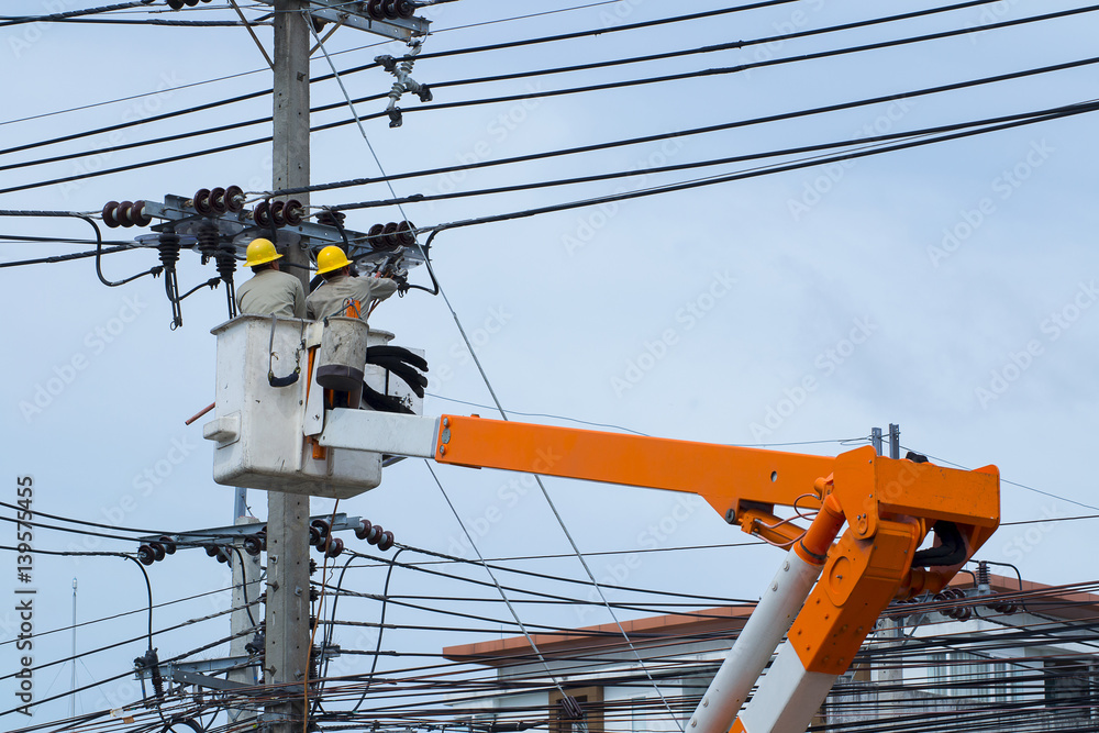 electricians repairing wire of the power line on electric power pole