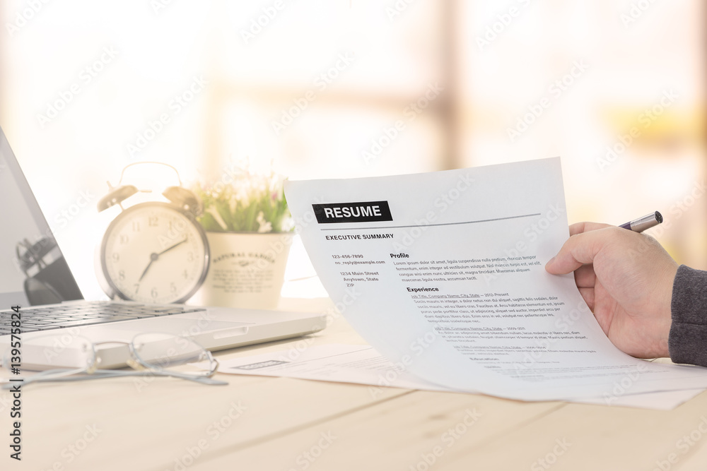 Naklejka premium Businessman or job seeker review his resume on his desk before send to finding a new job with pen, necktie, glasses and digital tablet.
