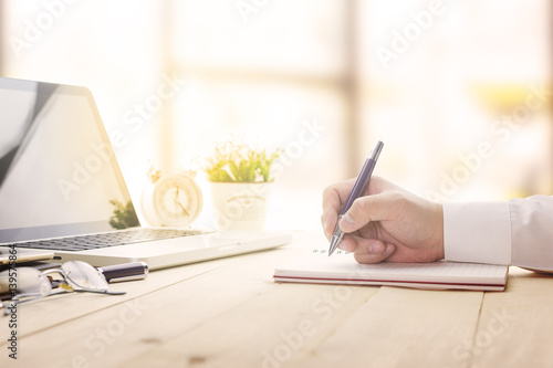 Businessman making notes at the office meeting with computer laptop and glasses.