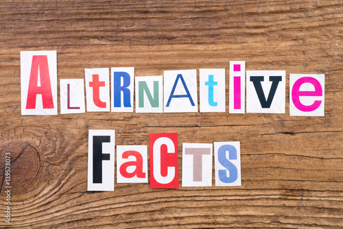 Phrase "Alternative Facts" in cut out magazine letters on wooden background 