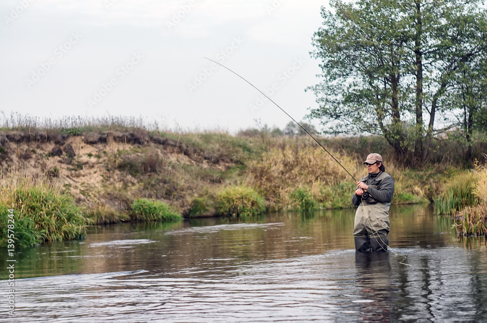 Happy fisherman pulls a fish .