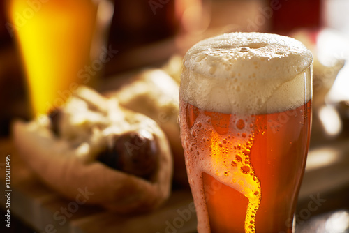Canvas Print IPA beer with overflowing foamy head in mug served with bratwursts