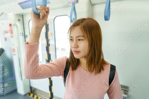 Woman traveler holding the train rails while taking sky train.