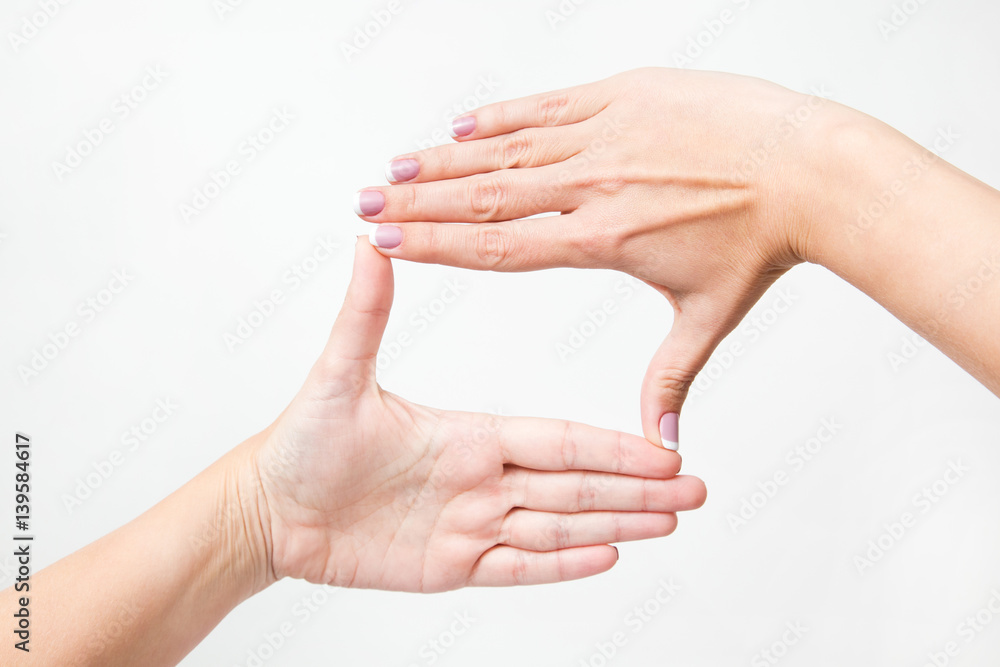 Close up of female caucasian hands isolated on white background. Young woman forming frame with her two hands as if looking at something virtual and invisible. Point of view shot.