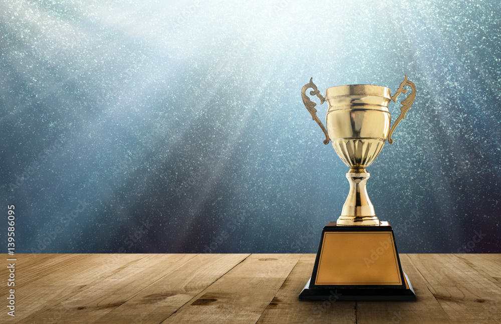 champion golden trophy on wood table with copy space and blue Twinkly