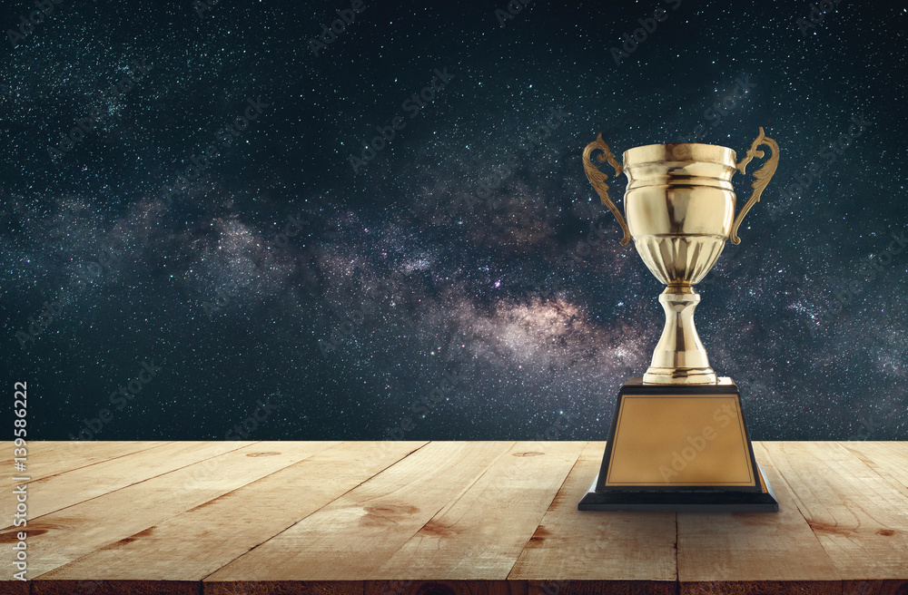 champion golden trophy on wood table with Milky Way background copy space  ready for your design. Stock Photo | Adobe Stock