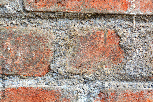 View of red brick wall with concrete fillings.