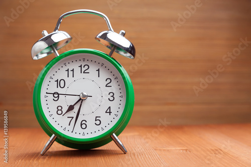 classic green alarm clock morning wake-up time on wood background