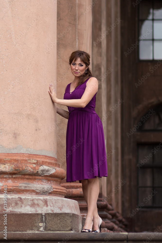 Beautiful woman in purple dress near the column. People