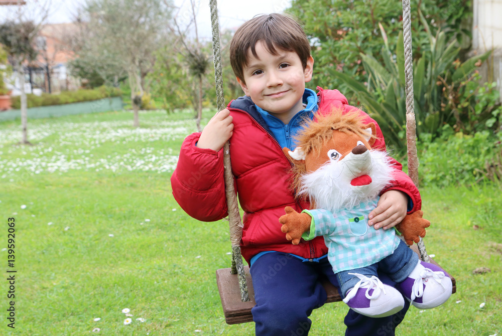 kid in a handmade swing with a teddy fox in the garden kid in a handmade swing with a teddy fox in the garden