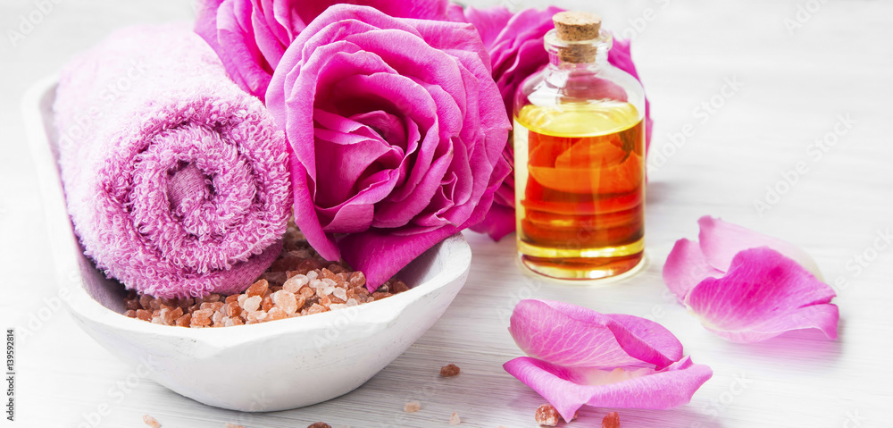 Roses spa setting with bath salt, roses flowers, bath rose oil, still life set Roses spa setting with bath salt, roses flowers, bath rose oil, still life set
