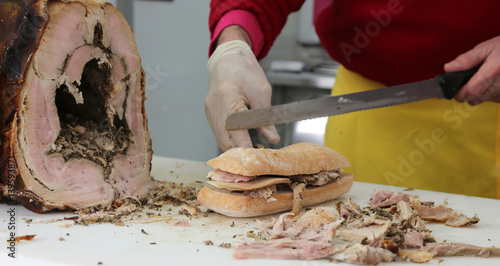 chef slicing the meat of pork to prepare a sandwich in the food