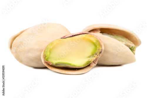 Salted pistachio nuts with a half on a white background closeup