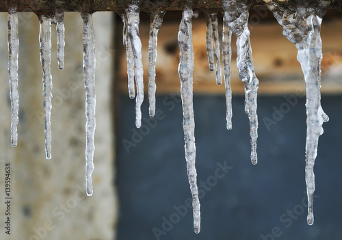 a variety of long icicles hanging on a rusty pipe
