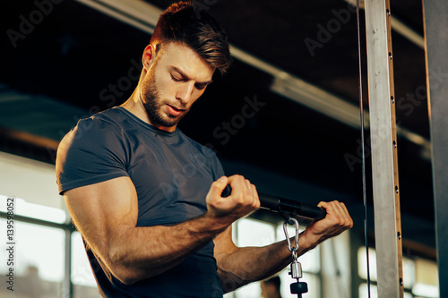 Fotobehang Handsome man doing heavy weight exercise for biceps in the gym