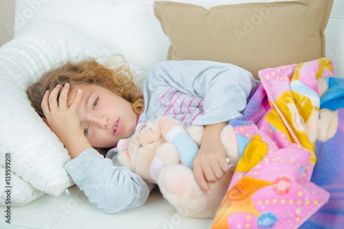 School girl lying down holding her head