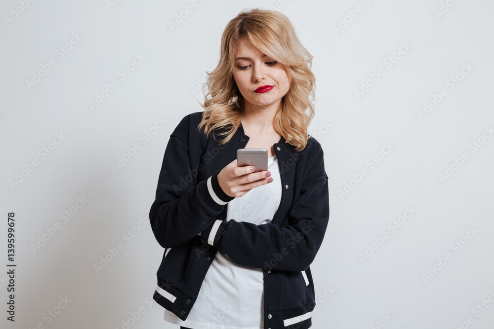 Unhappy upset girl reading message on her mobile phone Unhappy upset girl reading message on her mobile phone