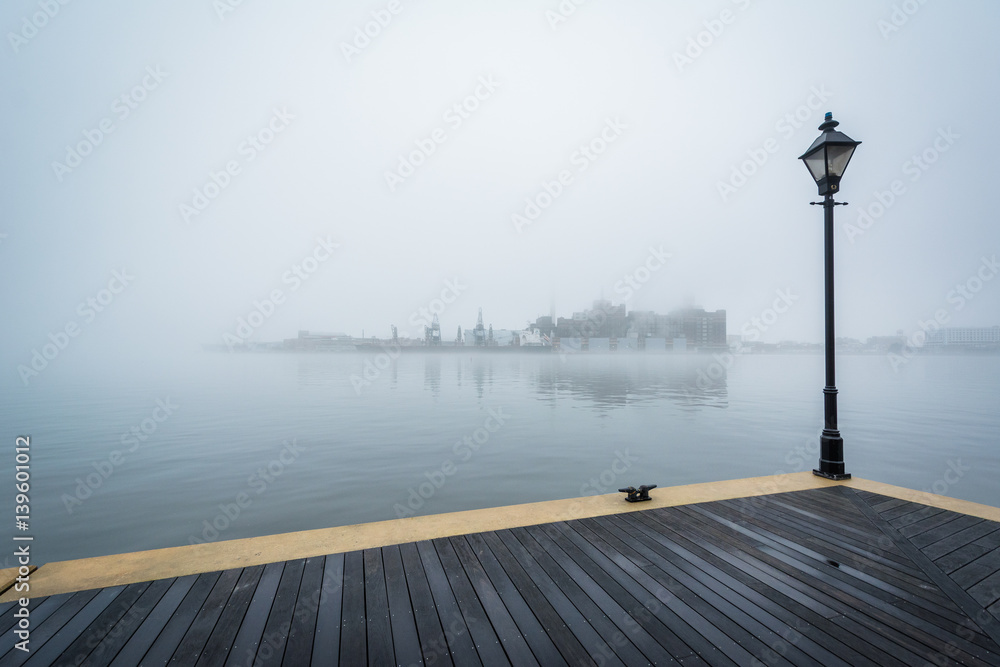 The Waterfront Promenade and fog over the harbor, in Fells Point, Baltimore, Maryland.