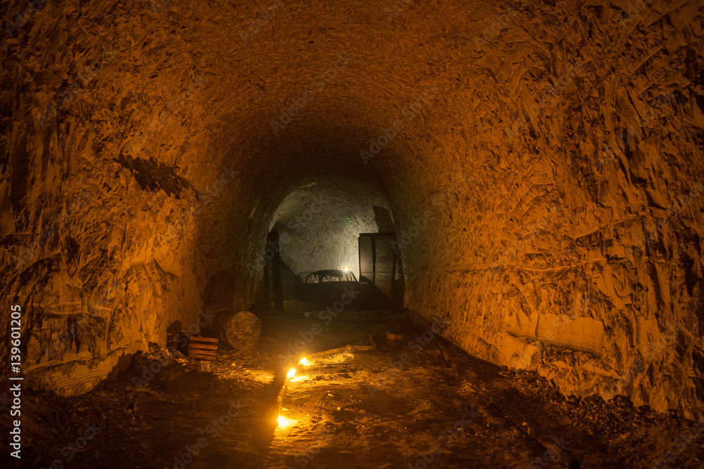 Abandoned chalk mine tunnel with traces of drilling machine and remnant of equipment, illuminated by candles, Belgorod, Russia