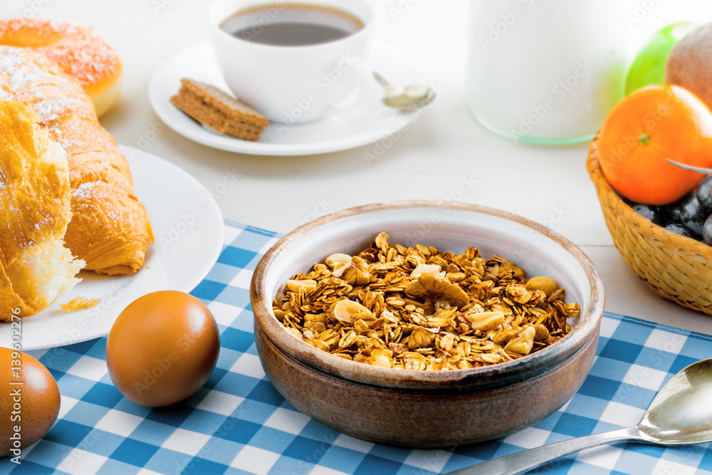 Granola, croissant, eggs, milk and fruits on a table. Healthy breakfast with coffee. International vegetarian meal. Granola, croissant, eggs, milk and fruits on a table. Healthy breakfast with coffee. International vegetarian meal.