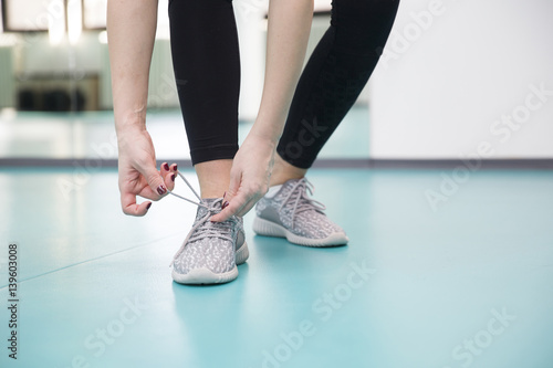 Young woman ties the laces on the shoes in the gym