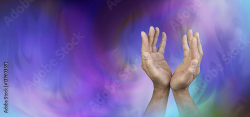 Seeking Support from Higher Powers - Male hands reaching up with an ethereal gaseous swirling blue and magenta energy field behind and copy space on left side