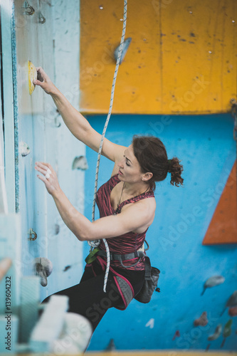 women climbs a route on the competition in a training room