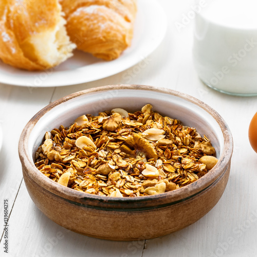 Granola, croissant, milk and fruits on a table. Healthy breakfast with coffee. International vegetarian meal.