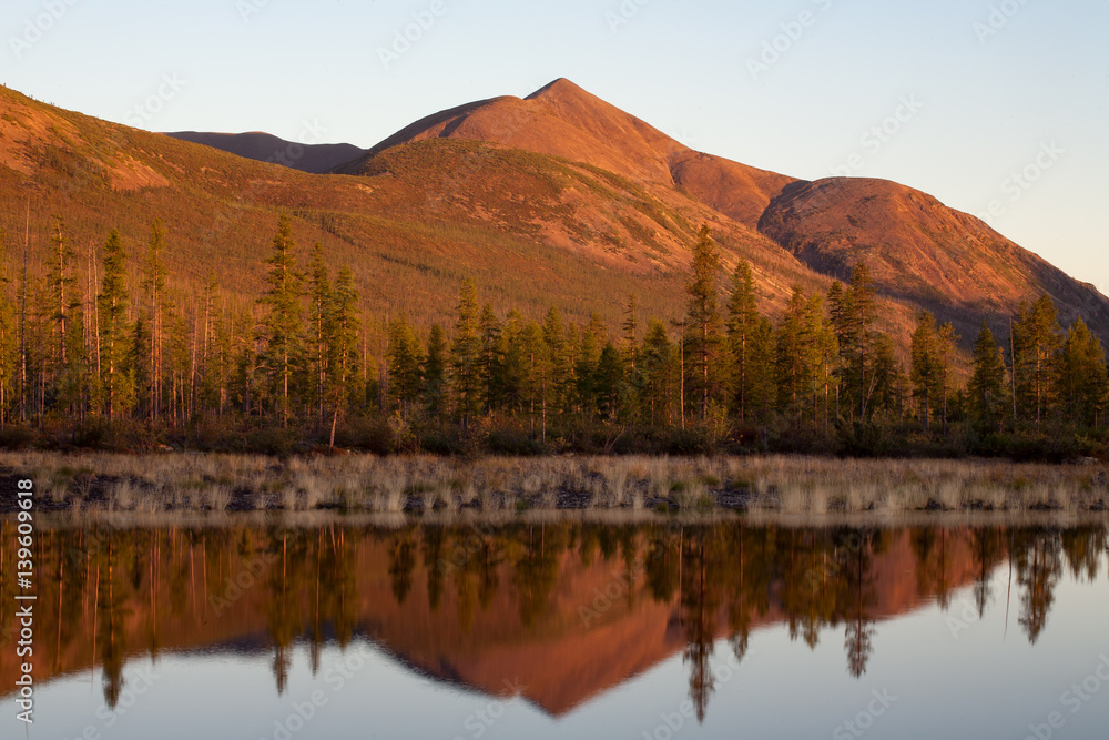 Mountain in red light and the reflection in the lake. Lake Labynkyr. Yakutia. Russia. Mountain in red light and the reflection in the lake. Lake Labynkyr. Yakutia. Russia.