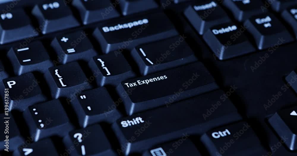 Close up of human hand pressing a tax expenses button on the computer keyboard Close up of human hand pressing a tax expenses button on the computer keyboard