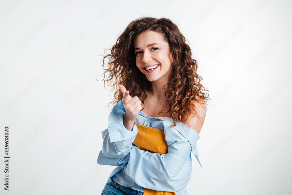 Beautiful excited young woman pointing at camera