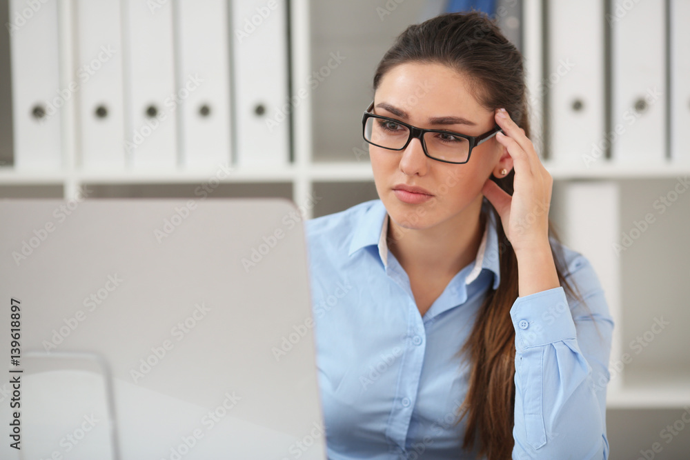 Business woman experiencing stress in the workplace, holding her hand behind her head Business woman experiencing stress in the workplace, holding her hand behind her head