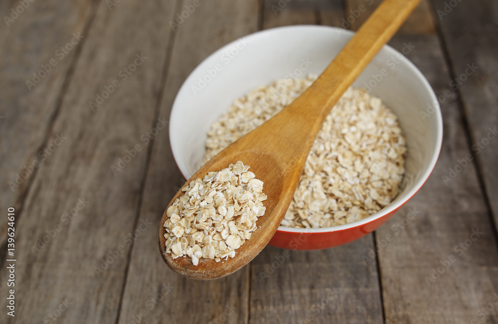 Dry oatmeal in wooden spoon, rustic background Dry oatmeal in wooden spoon, rustic background