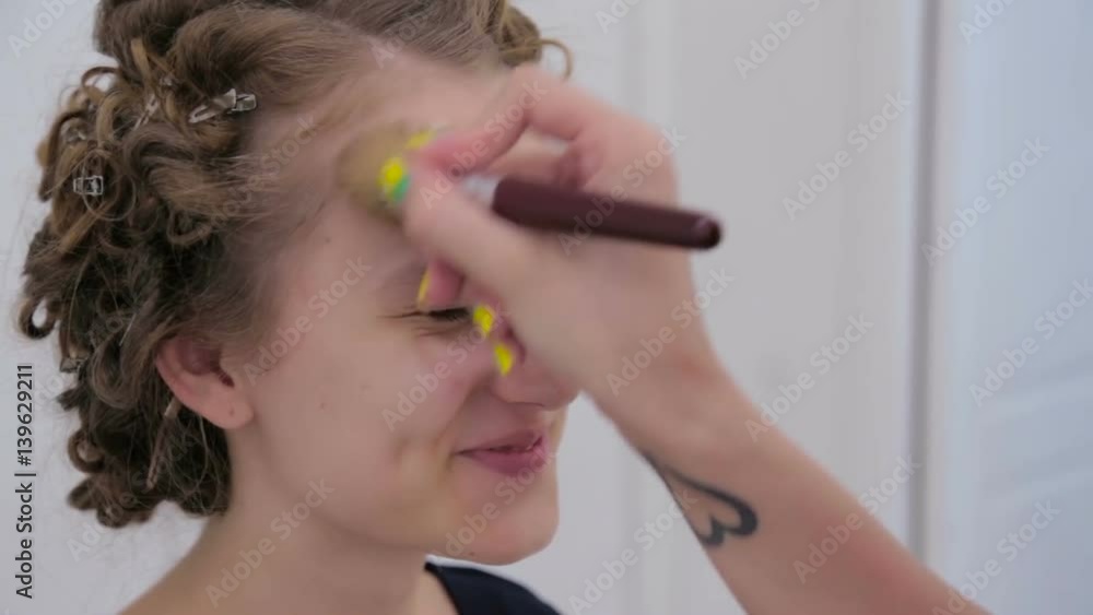 Makeup artist applying liquid tonal foundation on the face of teen girl in white make up room. Beauty and fashion concept Makeup artist applying liquid tonal foundation on the face of teen girl in white make up room. Beauty and fashion concept