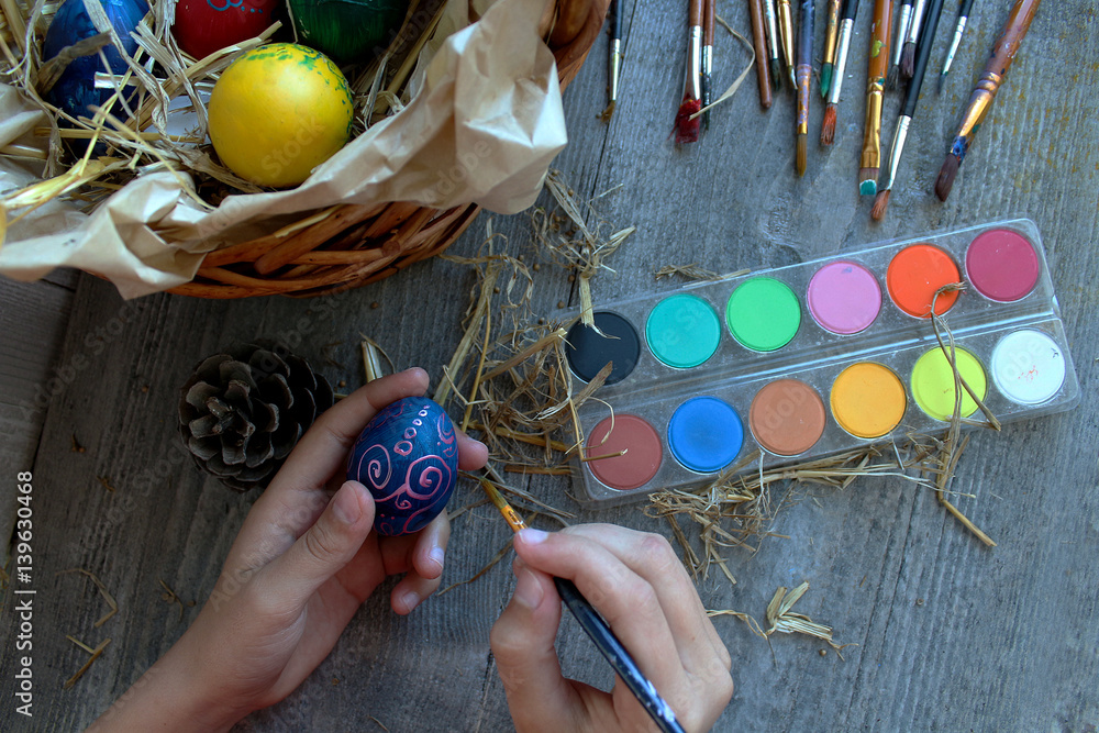 Women hands holding brushe and easter egg for coloring