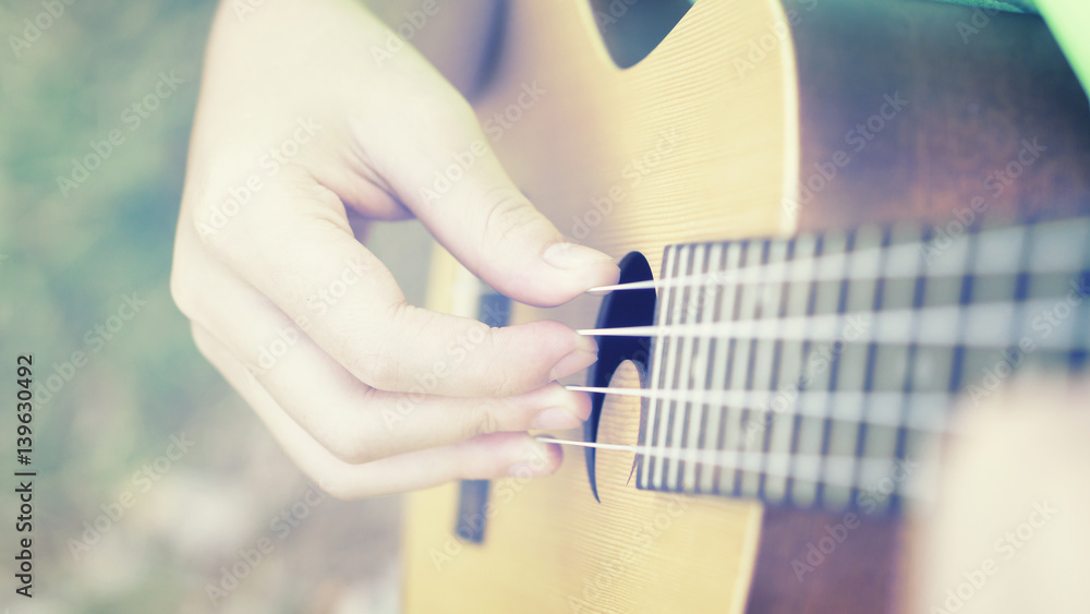Fototapeta premium woman handicraft playing ukulele. Hands playing a musical instrument.relaxing and free people on Ukulele (mini guitar) at the park,sunset vintage tone,selective focus,copy space for advising
