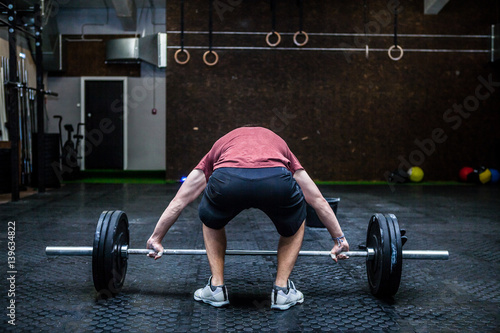 Young man with weight training equipment in sport gym