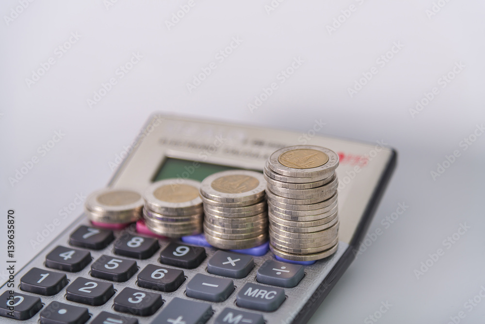Increasing columns of coins, piles of coins arranged as a graph and calculator on white background Increasing columns of coins, piles of coins arranged as a graph and calculator on white background