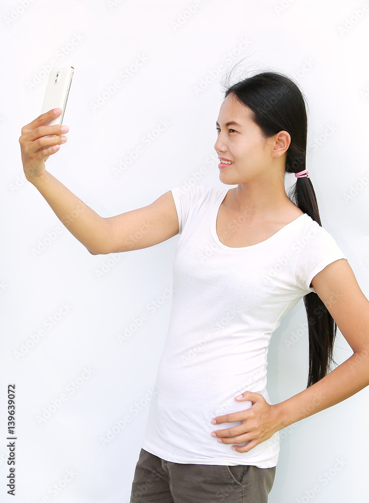 Asian girl taking pictures of herself through cell phone on white background Asian girl taking pictures of herself through cell phone on white background