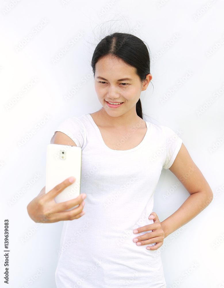 Asian girl taking pictures of herself through cell phone on white background Asian girl taking pictures of herself through cell phone on white background