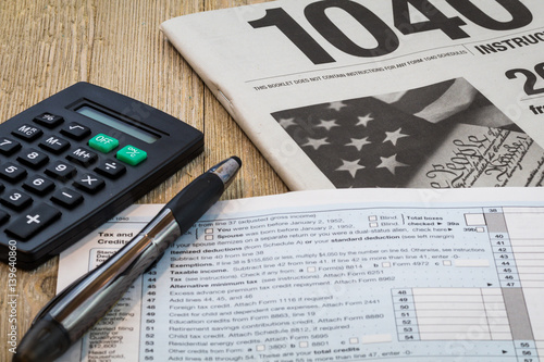 Tax preparation form US 1040 and tax tables, generic (no year specified) with calculator and pen on wooden board