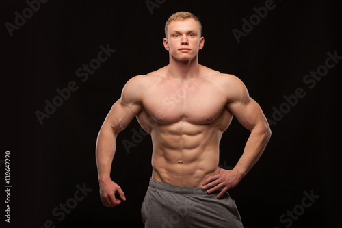 Athletic handsome man fitness-model showing six pack abs. isolated on black background with copyspace