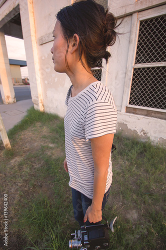 Girl Shooting 16mm Film Camera Next to Building