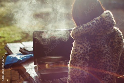 Girl cooking in faux leopard coat while camping.
